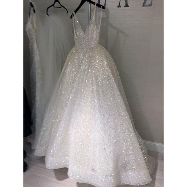 Pure white wedding evening dress featuring a deep v-neckline and delicate spaghetti straps crafted from sheer tulle adorned with sparkling sequins.
