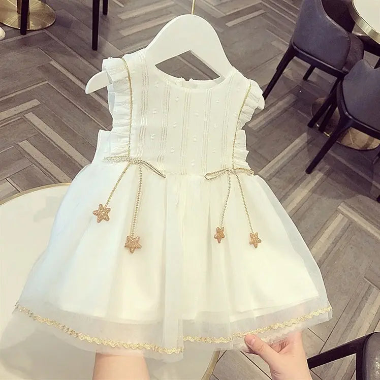 White sleeveless baby gauze dress summer princess dress featuring a delicate ruffled bodice, gold star-shaped tassels on the waistband, and a sheer layered skirt trimmed in gold lace.