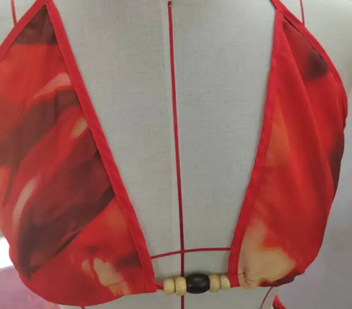 red sheer halter top with a bold abstract pattern and wooden bead accents as part of a zebra printed bikini strappy casual suit with a strappy skirt.