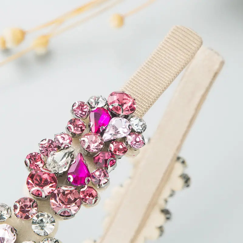 a baroque vintage court style headband featuring a cluster of pink and clear rhinestones on a beige elastic band