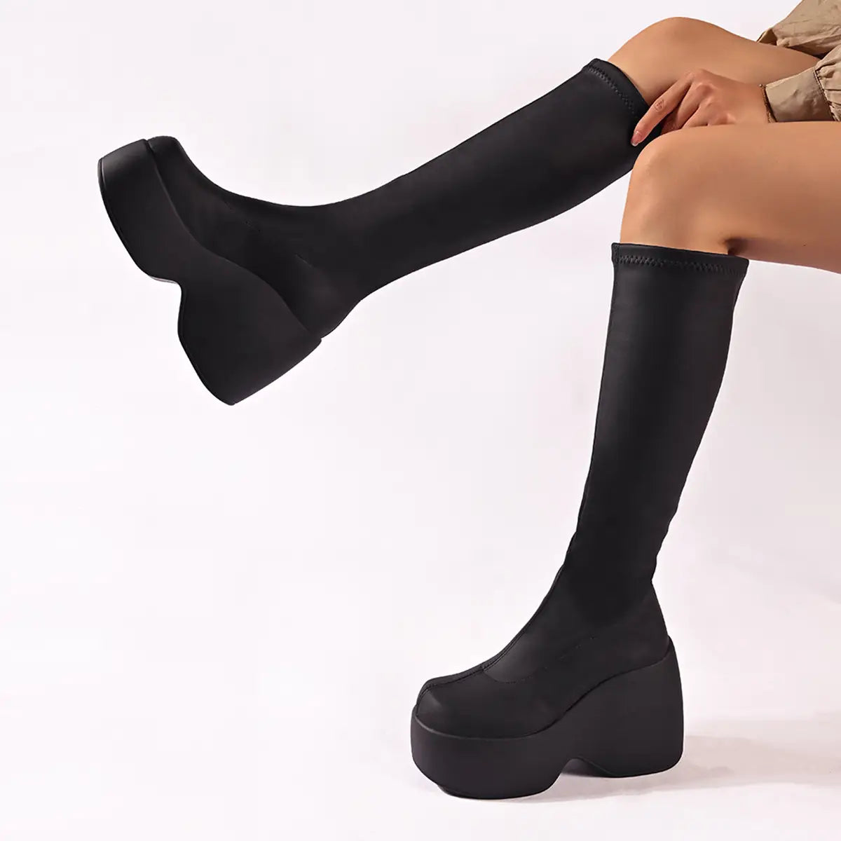 Black platform knee high elastic leather boots featuring a stretchy seamless fabric upper and thick chunky soles.
