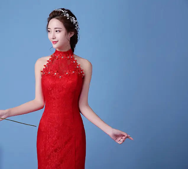 A woman wears a vibrant red big red wedding dress in lace mermaid style with high neck floral embroidery and beading along the neckline.