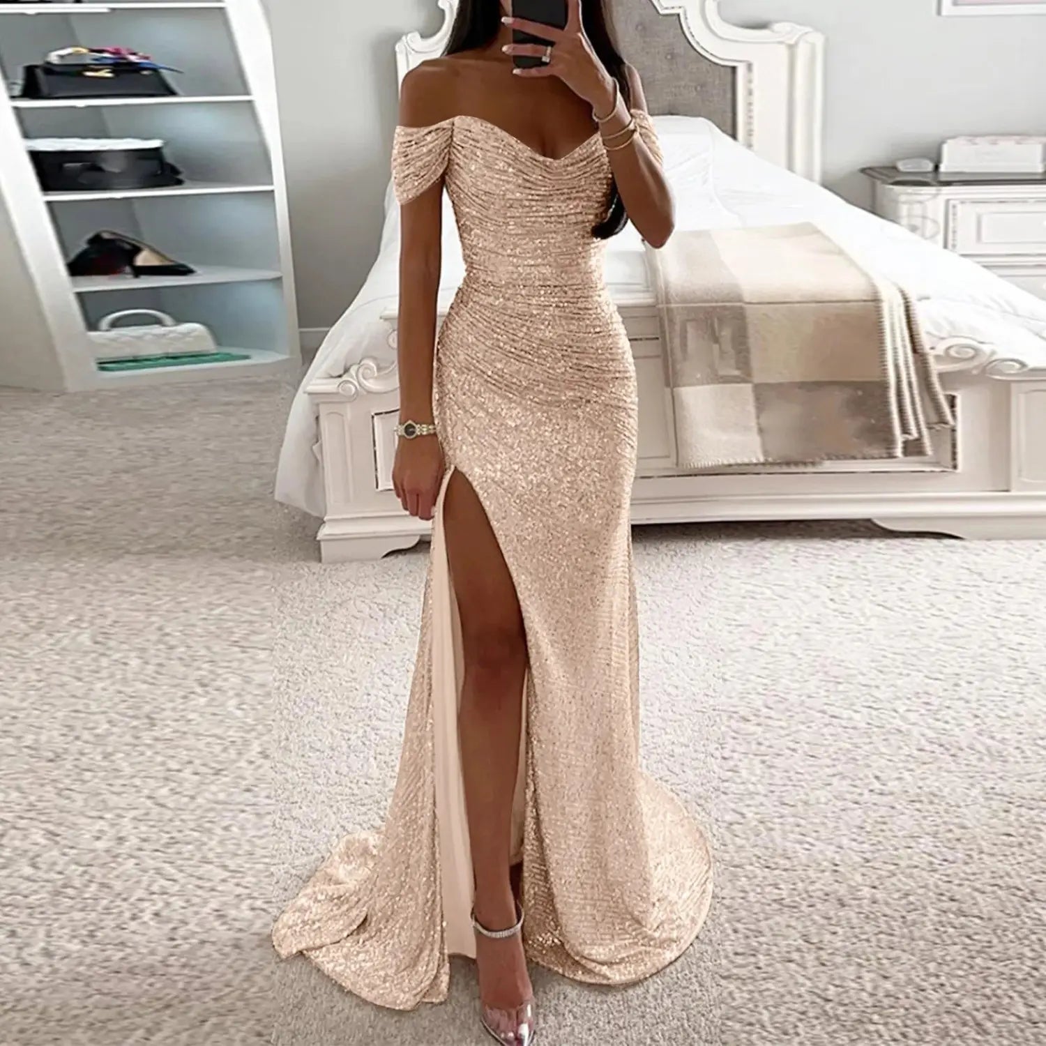 A shimmering rose gold sequined female creative solid off-the-shoulder gown with a high slit and flowing train featuring solid color sparkling fabric.