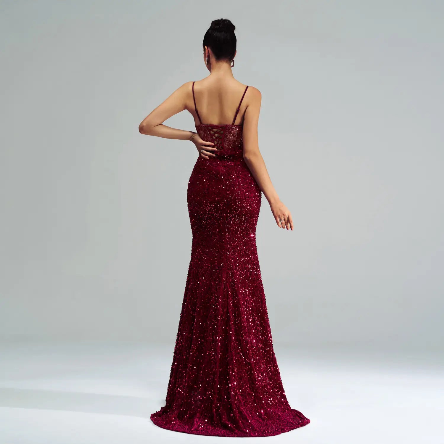 A shimmering burgundy mermaid-style sleeveless sequined high slit evening dress with delicate lace detailing at the back.