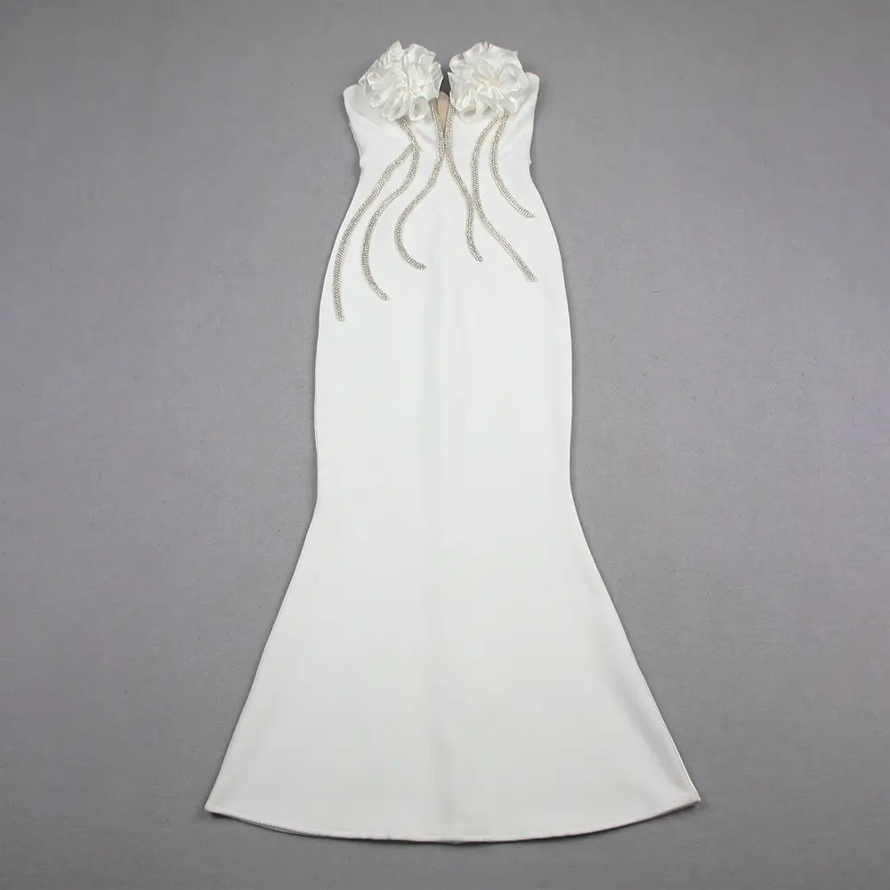 a sleek white mermaid-style gown with a strapless design featuring two large satin ruffled flowers at the neckline and cascading silver beaded strands, embodying the style temperament socialite and socialite flower chain evening dress elegance.