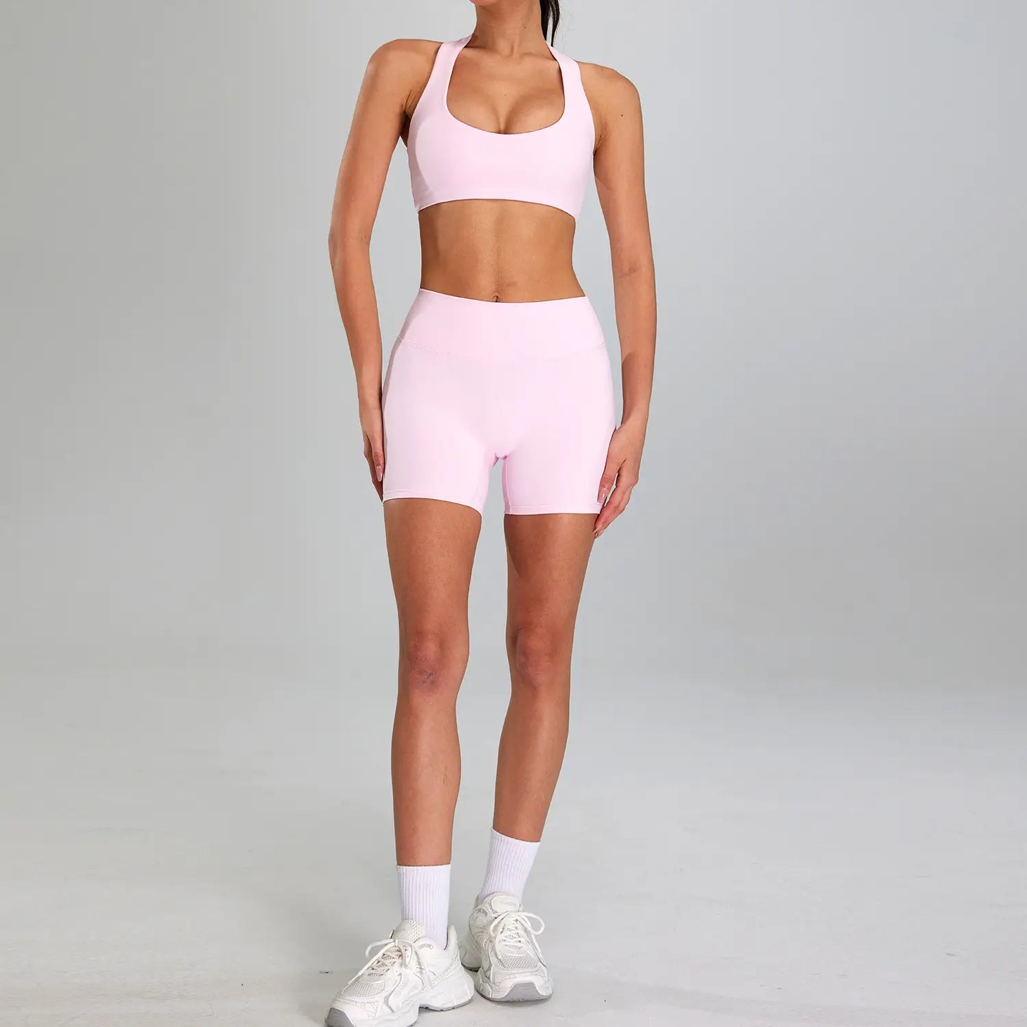 A soft pink form-fitting athletic two-piece sports suit outdoor made of stretchy fabric designed for outdoor running nude activities.