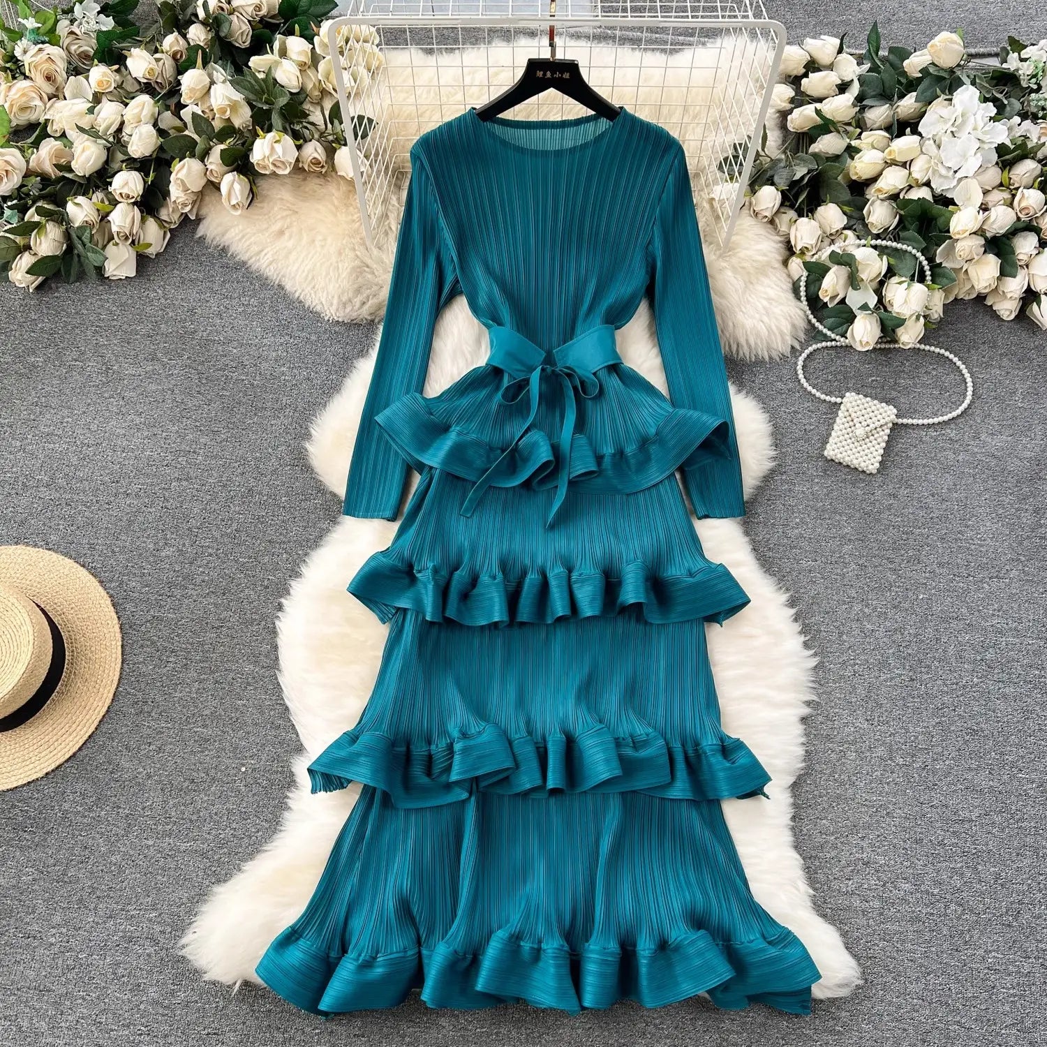 olive green cake heavy industry pleated long dress with a teal pleated tiered design, long sleeves, and a matching belt featuring a heavy industry pleated slim silhouette.