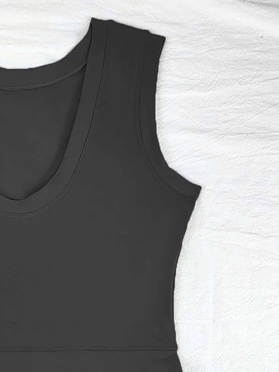 black sleeveless top with a scoop neckline and smooth form-fitting fabric paired with a sleeveless side slit yoga tennis skirt sport dress in black for athletic and casual wear.
