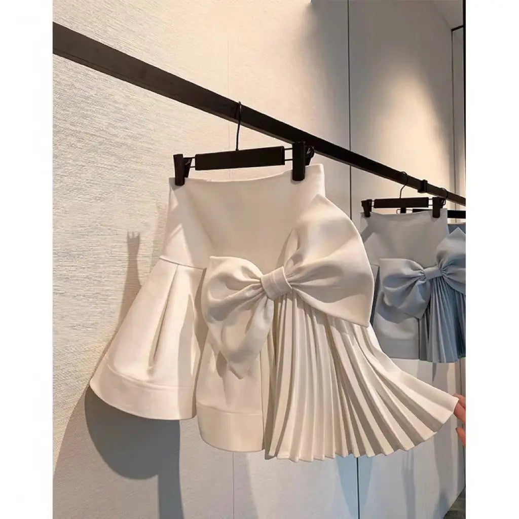 a white high waist slimming pleated skirt featuring a large structured bow at the waist