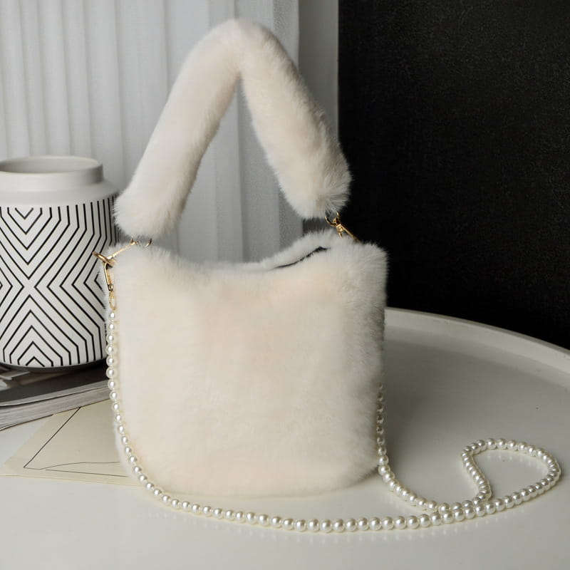 Off-white checkerboard plush bucket bag with a soft faux fur texture, plush handle, and delicate pearl chain design strap.