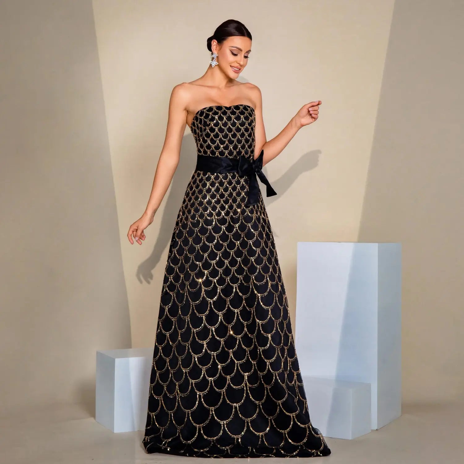 black strapless large swing sequined evening dress adorned with shimmering gold fish-scale embroidery and a matching satin sash tied in a bow at the waist