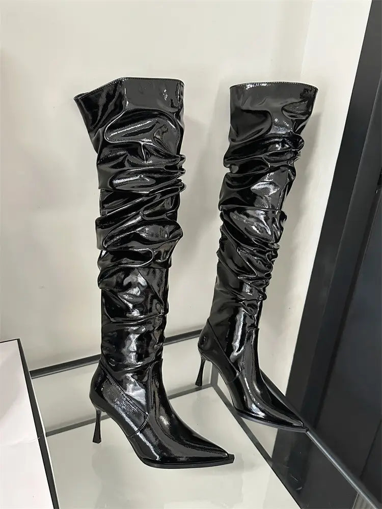 black patent leather thigh high boots with a ruched design and sharp autumn stiletto heel in heel pile style