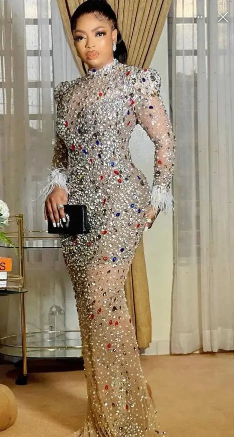 A shimmering silver feathered rhinestone mesh stretch slim dress with long sleeves and a mermaid-style silhouette adorned with multicolored sequins.