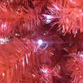 A vibrant red 6 foot articulated fir Christmas tree with glowing white LED lights and fringed branches