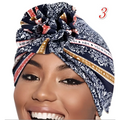 A navy blue patterned vibrant printed headband with white floral and gold trim tied in a decorative knot at the top