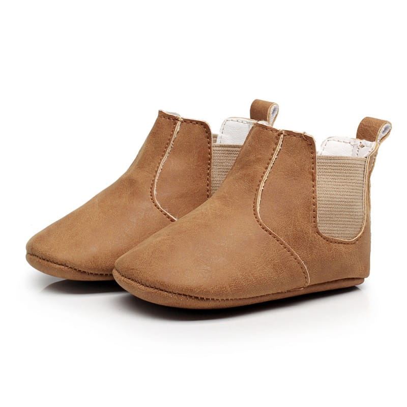 Soft suede baby shoes baby xie toddler booties in tan with elastic side panels and white interior lining.