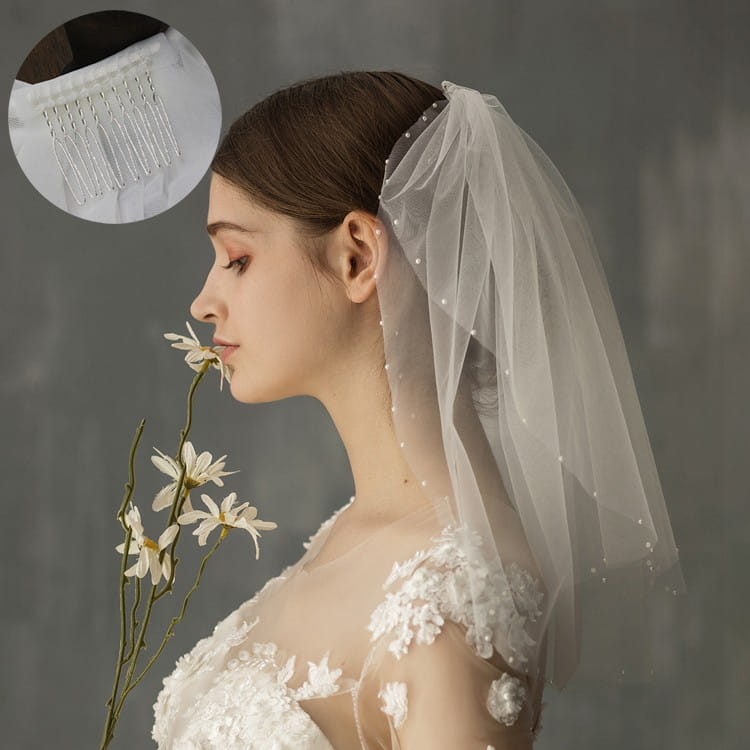 A delicate retro short wedding lace floral veil in white tulle adorned with pearl-like embellishments and a matching silver comb for a short wedding bride headdress.