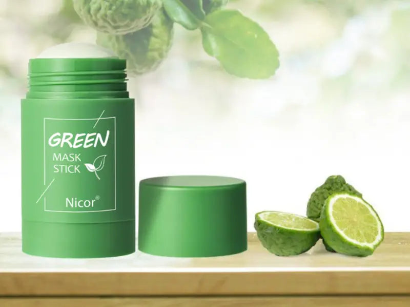 Green cylindrical cleansing green tea and eggplant oil control mask stick with matching cap positioned beside sliced limes.