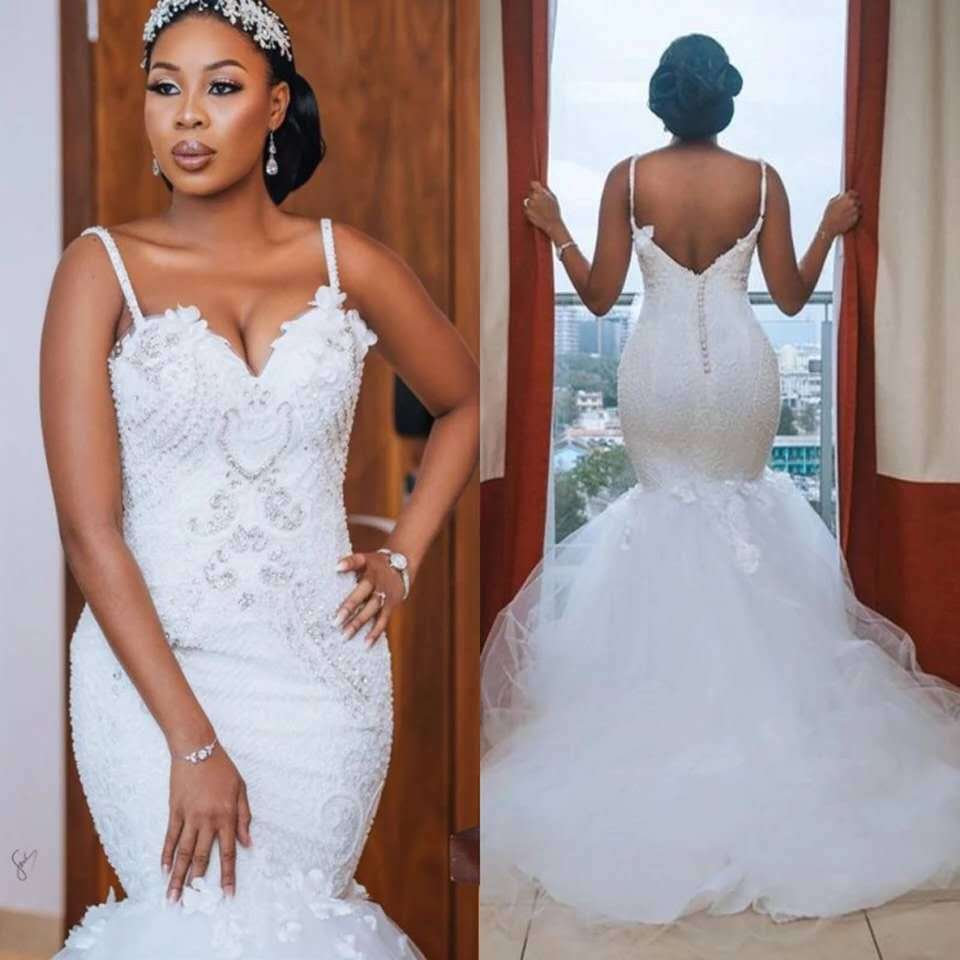 White lace sleeveless big tail African mermaid wedding dress featuring a fitted bodice with intricate lace detailing and sparkling embellishments as the main fabric.