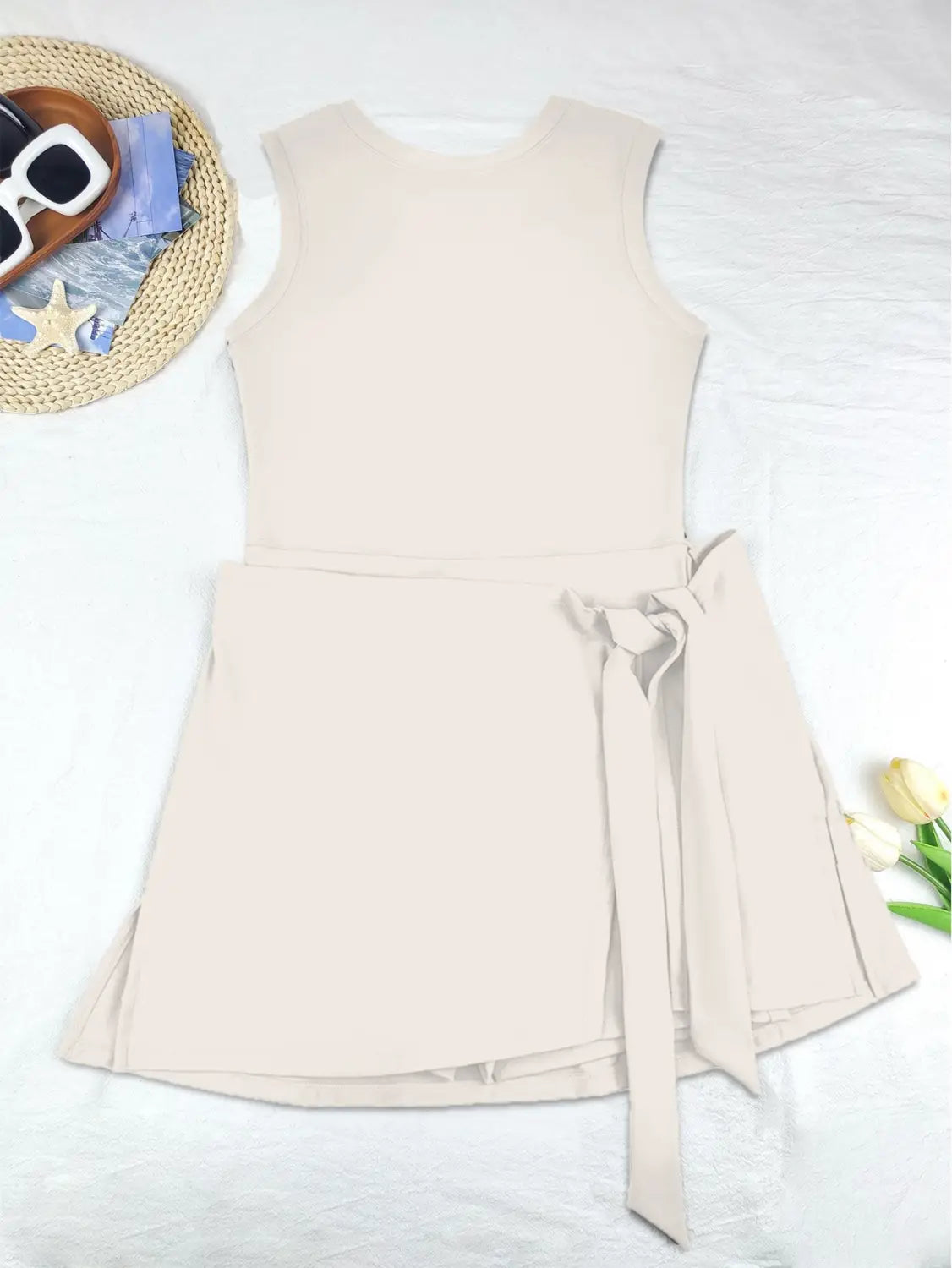 beige sleeveless skirt sport dress with a tied waistband and flared skirt suitable as a yoga tennis skirt.