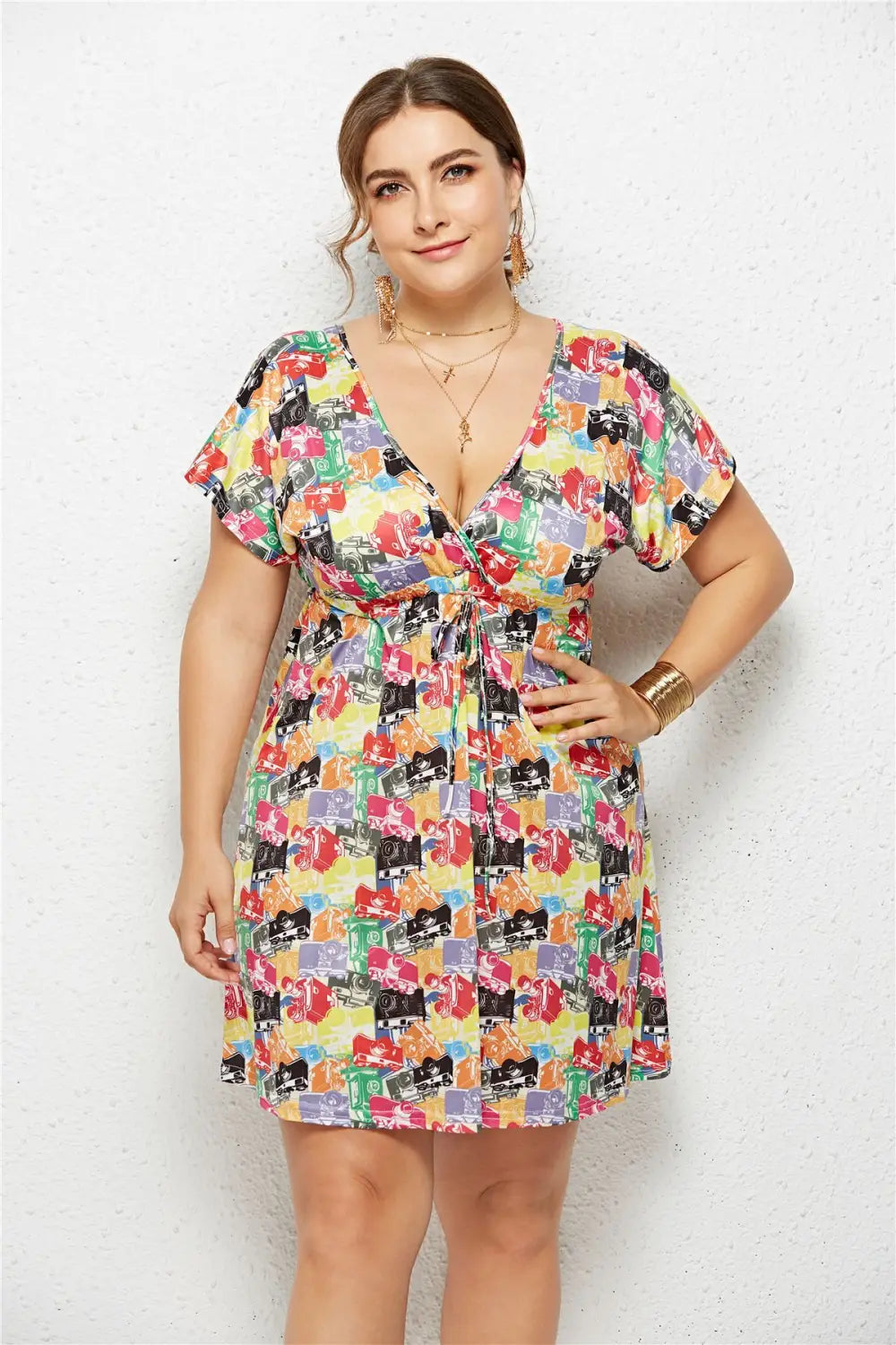 A vibrant short-sleeved printed deep v-neck dress with an elastic waist featuring a colorful pattern of cartoon-style cameras on a yellow background.