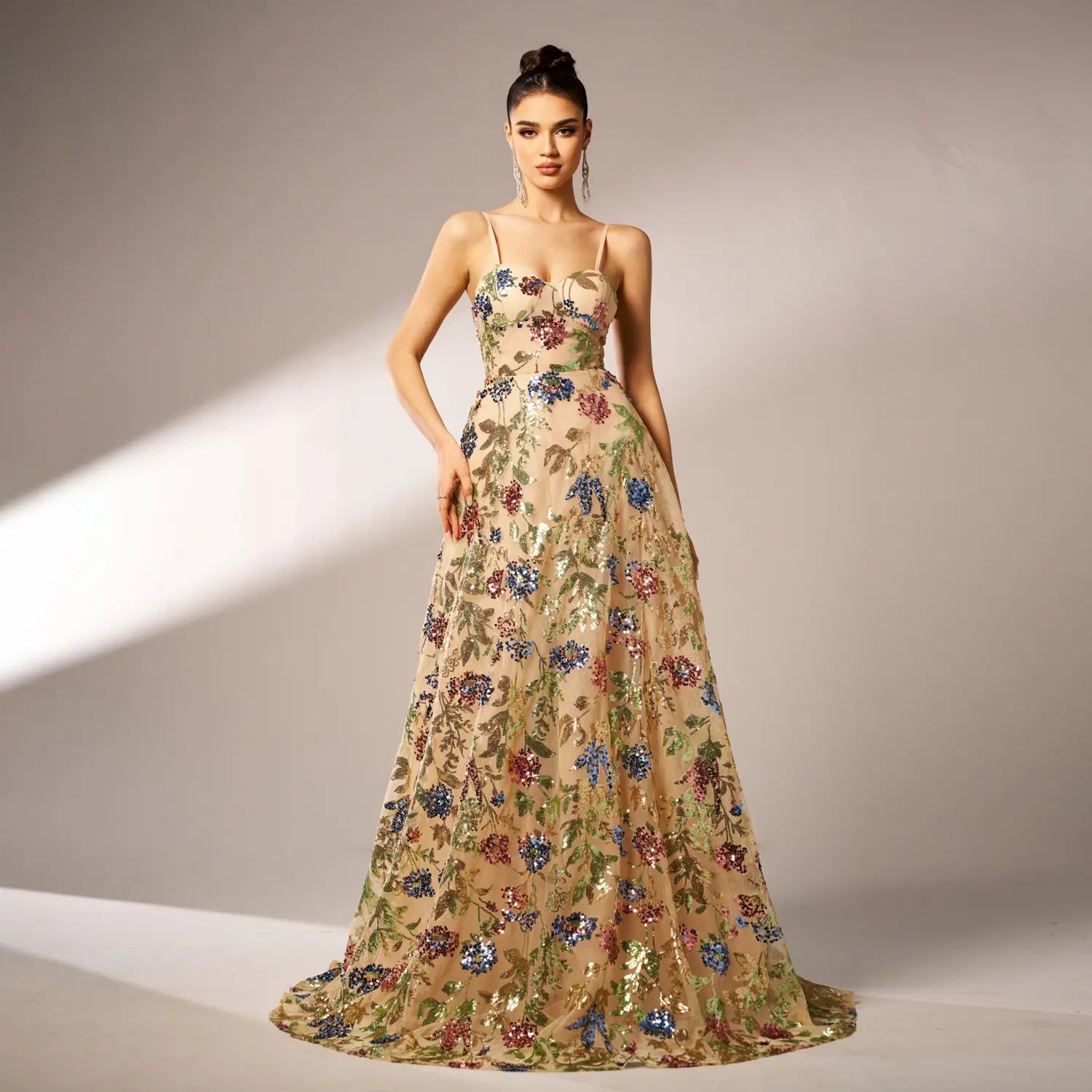An elegant sleeveless sequined suspender evening dress in champagne color features intricate floral embroidery in vibrant blues reds and greens on a floor-length gown.