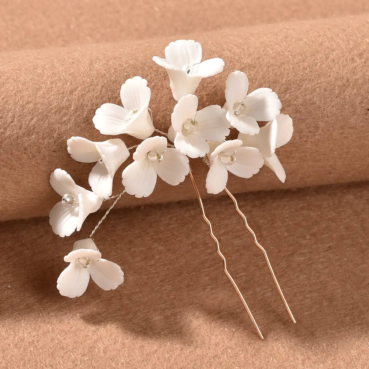 White three dimensional flower u shaped hairpin made of white ceramic with delicate petals and tiny clear beads at the center.