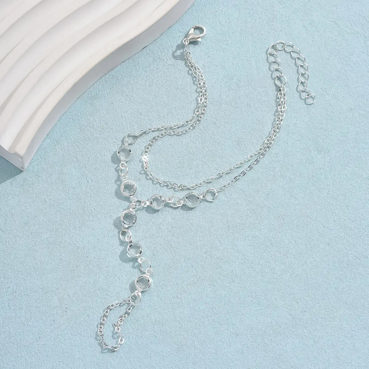Silver chain anklet with clear faceted gemstones and lobster clasp designed as an american fashion minimalist bracelet ring.