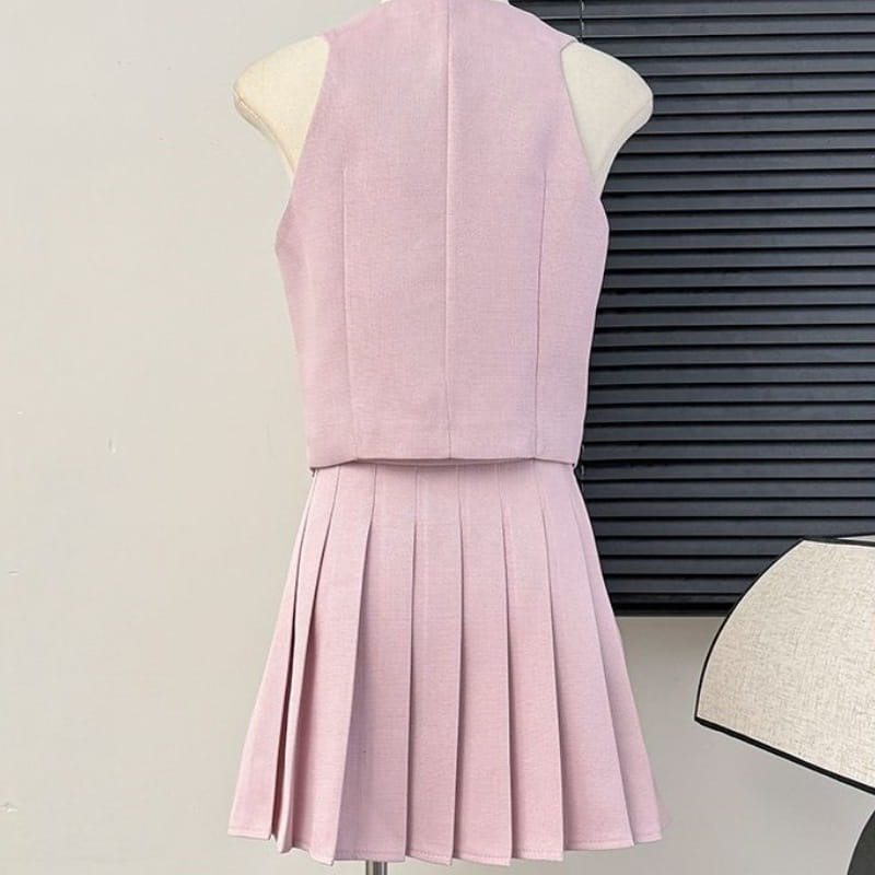 a soft pink sleeveless two-piece set featuring a v-neck vest with a fitted bodice and a high waist pleated skirt.