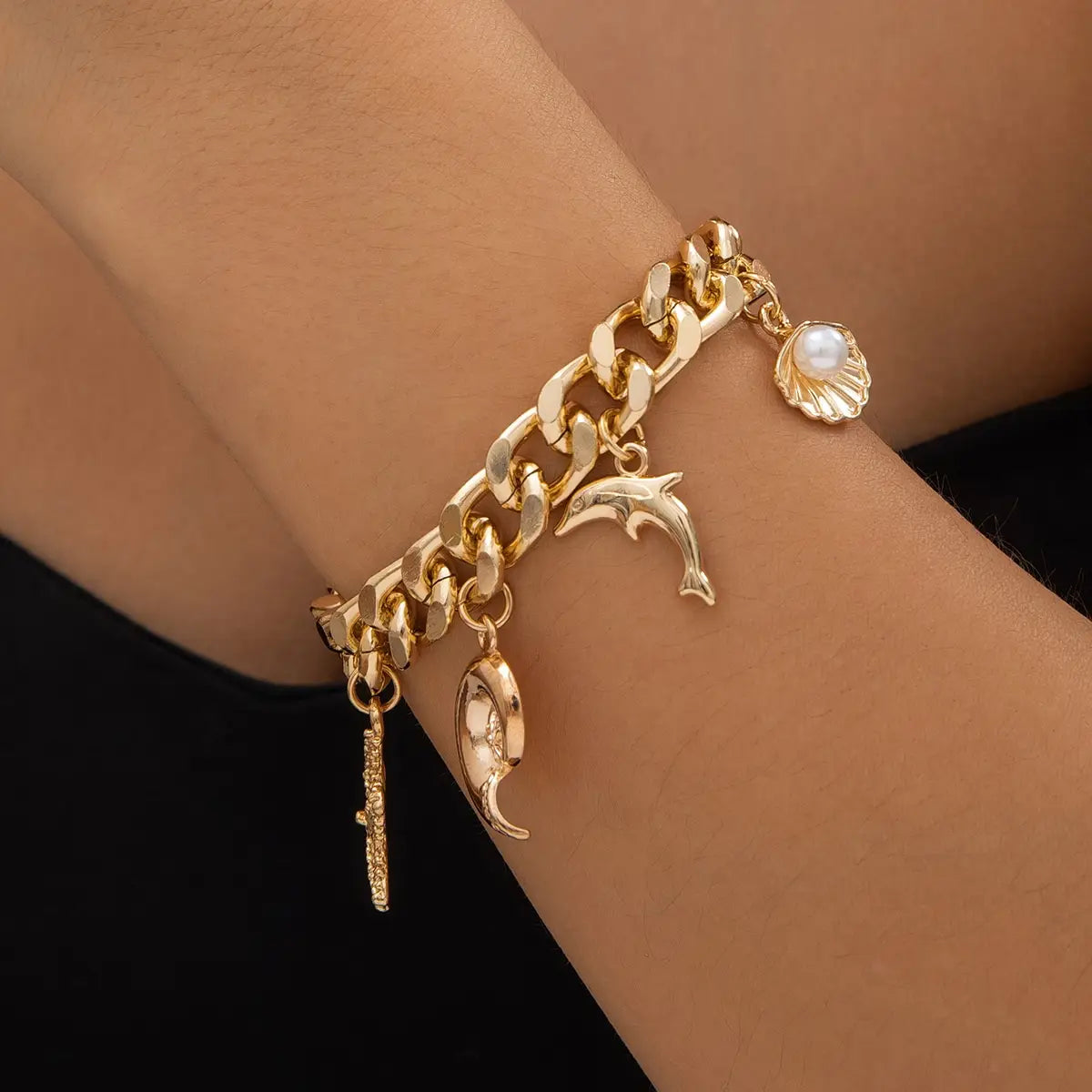 gold-toned bracelet set featuring a conch dolphin charm, a seashell pendant with a pearl, and a crescent moon charm from the boho conch dolphin starfish choker necklace bracelet set.