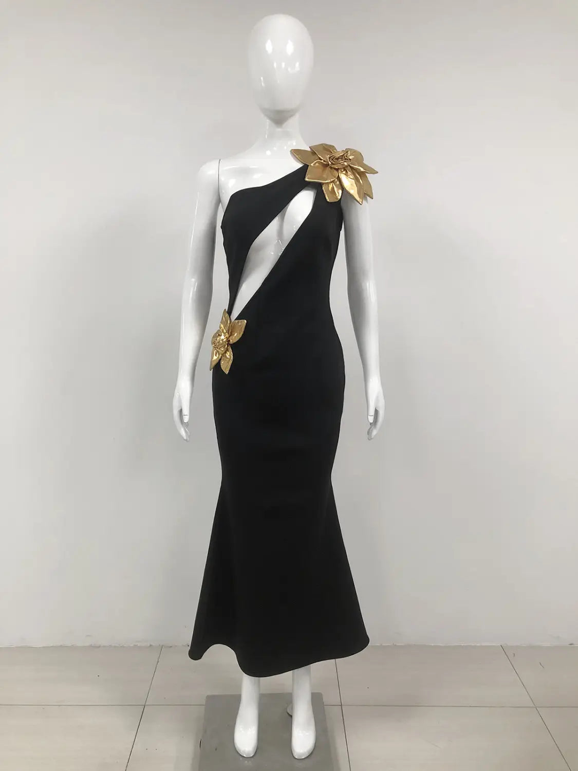 Black satin bandage golden flower maxi dress featuring a black one-shoulder mermaid design adorned with gold floral embellishments.