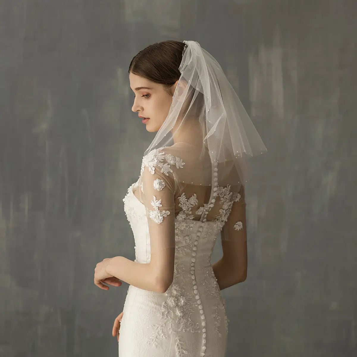 A delicate sheer white retro short wedding veil with subtle floral lace embroidery adorns the wedding bride headdress.