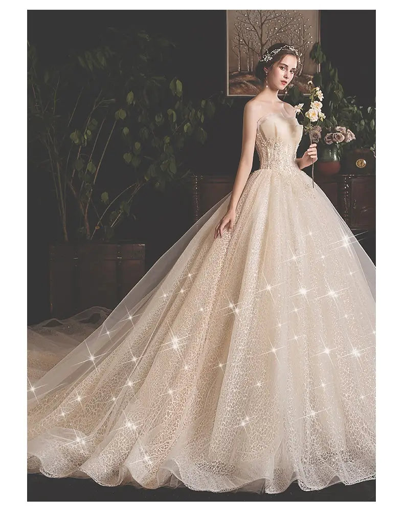 A strapless ivory lace bride summer tube gown with a fitted bodice and a voluminous mori style trailing tulle skirt.