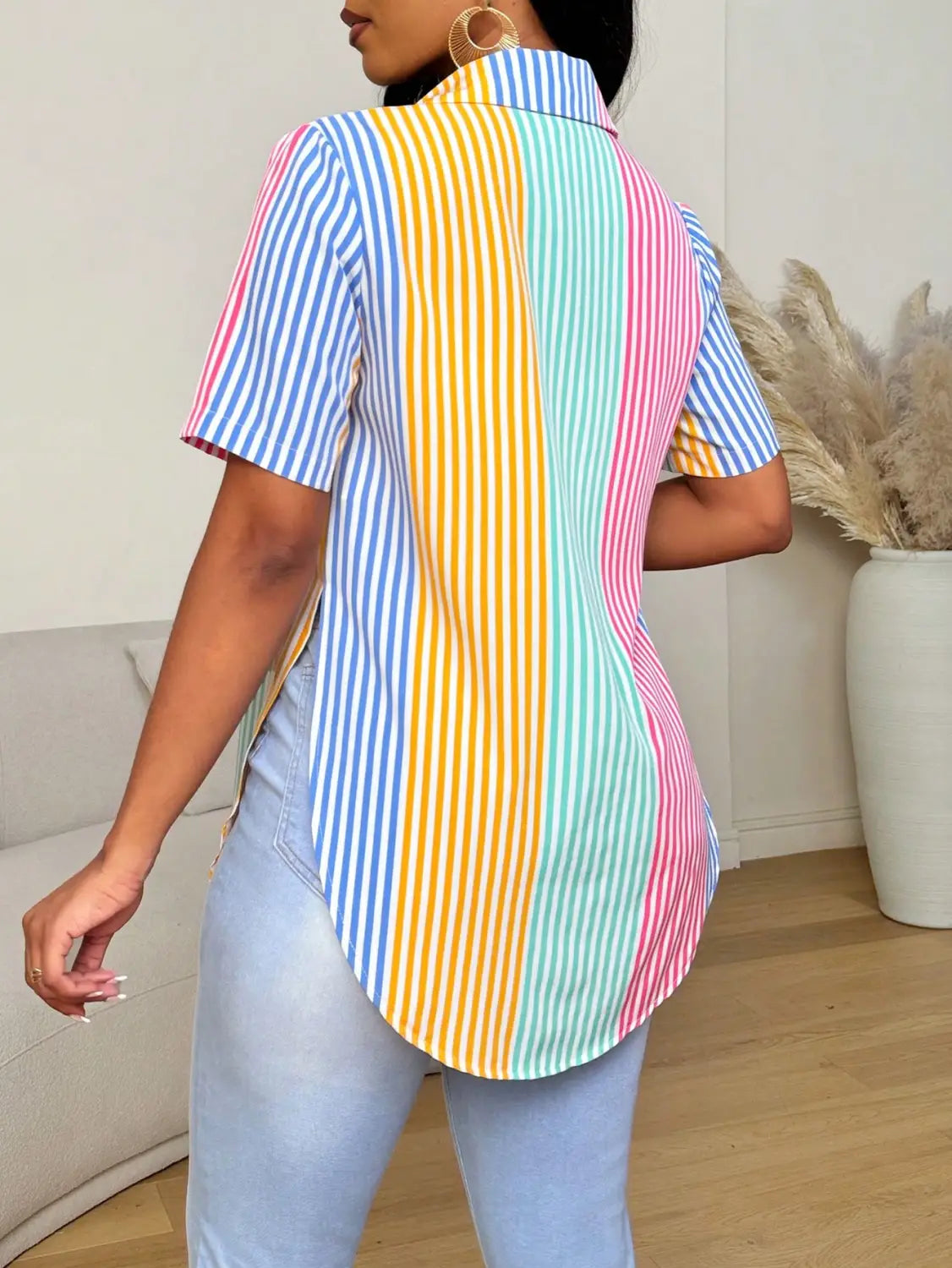 A vibrant short-sleeved button asymmetrical hem shirt featuring a contrast color striped pastel blue yellow mint green and pink color striped print.