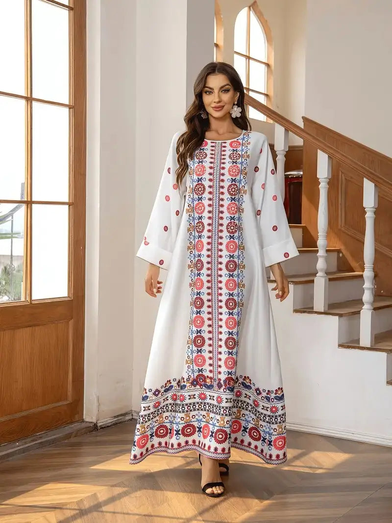 A white long sleeve maxi dress featuring intricate red blue and gold floral print embroidery with rhinestone bead embellishments along the front panel sleeves and hem.