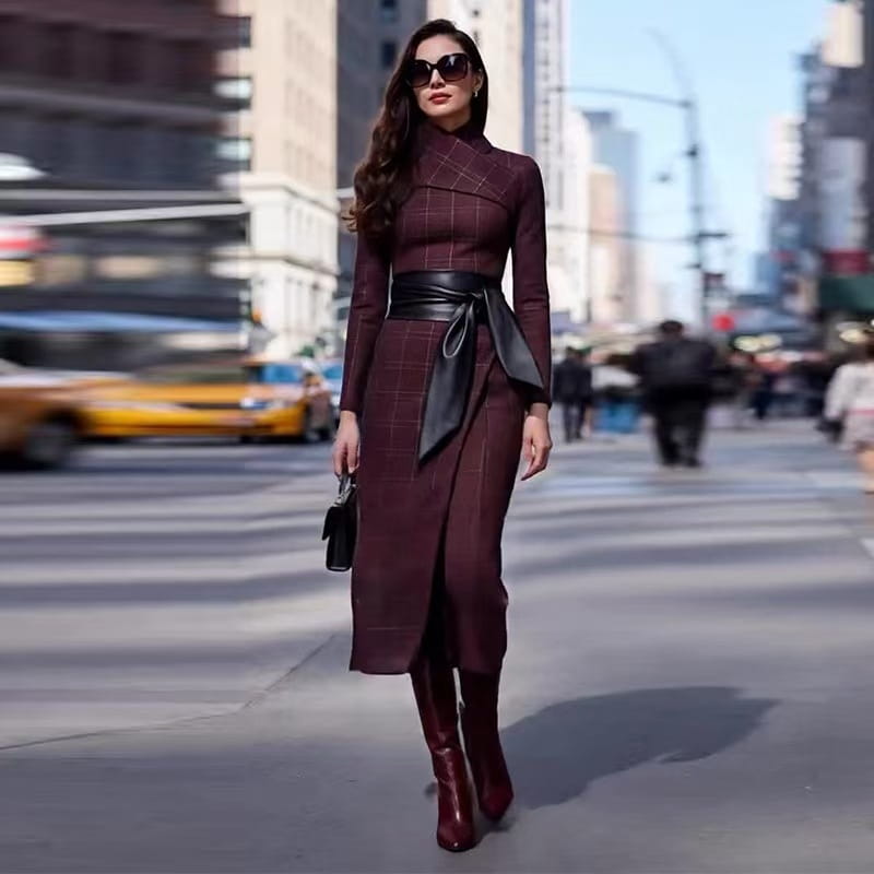A stylish burgundy maroon plaid wide-waisted belted dress with a high neckline and long sleeves featuring a black leather belt tied at the waist.