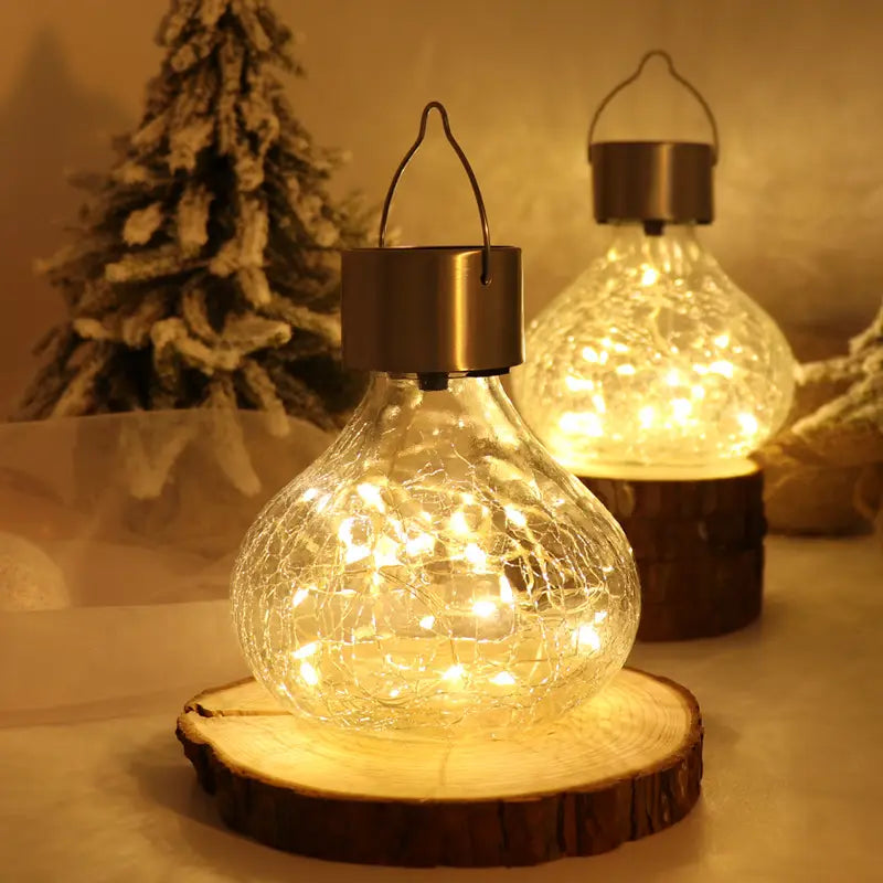 Glass lantern solar crackle glass night light with brass-colored solar cap and hanging loop, featuring warm white fairy lights inside crackled glass for night light ambient use.