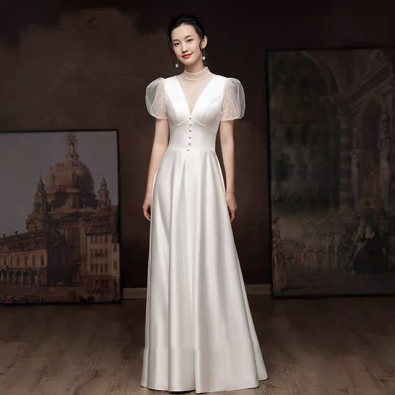 A flowing white satin wedding dress with sheer puff sleeves and a v-neckline designed for engagement wedding occasions.
