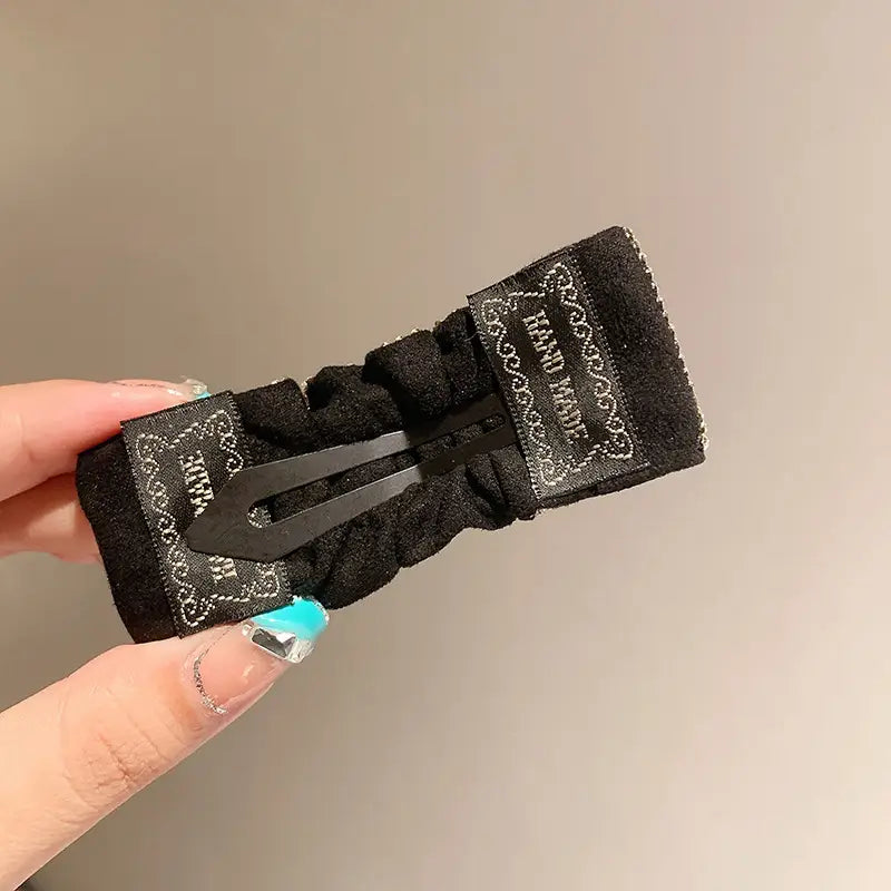 black velvet pleated bb clip with a decorative bandana-style label and metallic clasp featuring hot rhinestone details