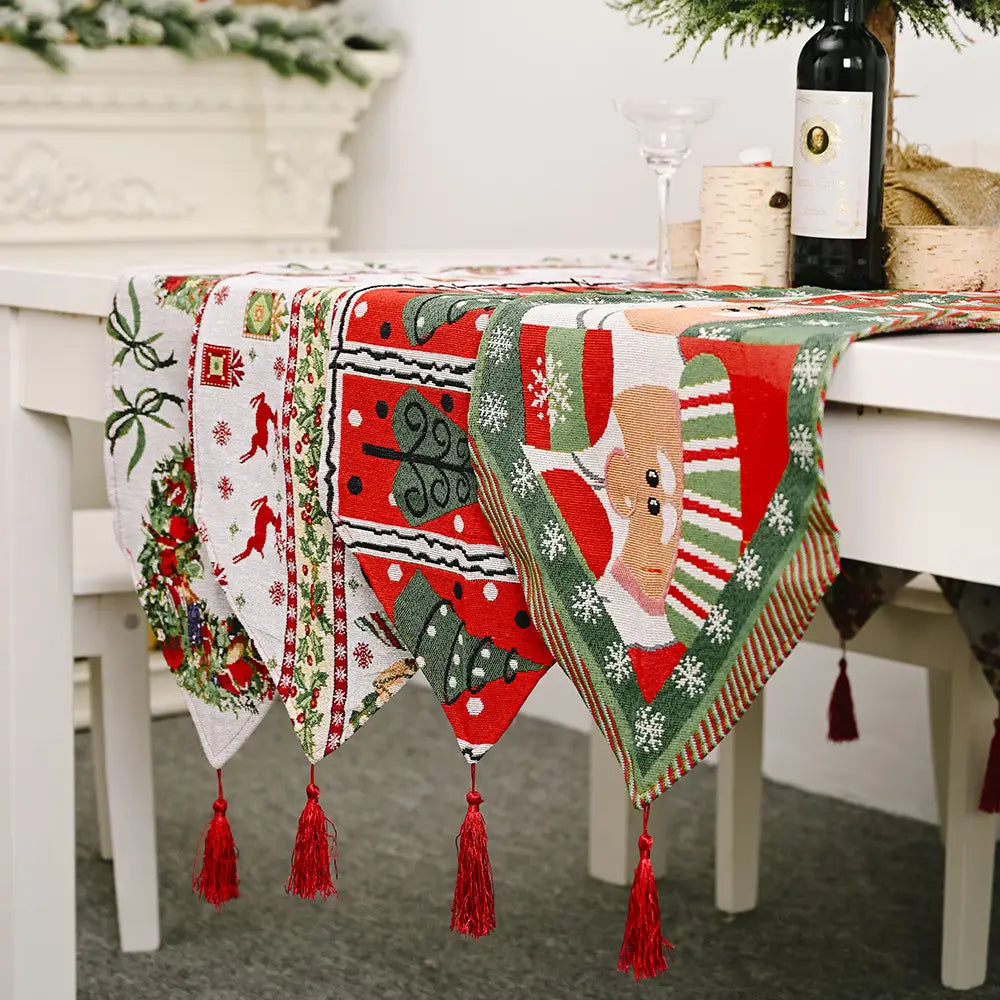 Woven christmas table runner with tassels in red green and white featuring festive patterns of reindeer trees snowflakes and santa claus face for christmas table decoration.