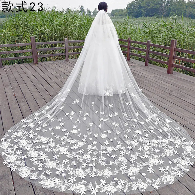 a long white bridal veil in wide style featuring delicate floral lace appliqués along the hemline measuring meters wide suitable for weddings