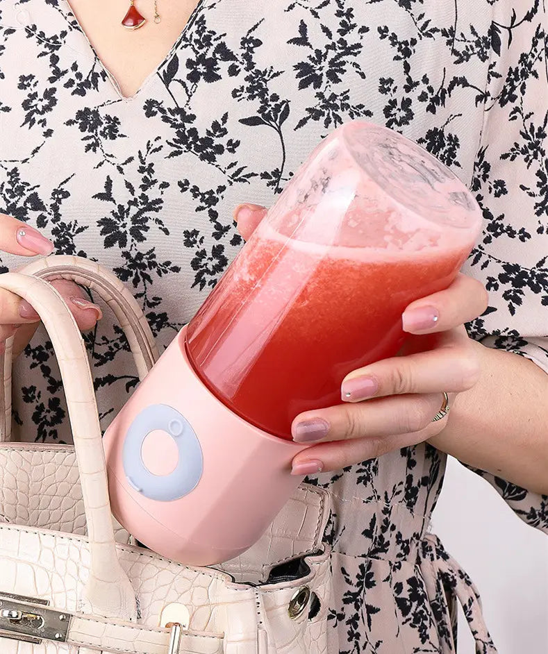 portable usb automatic mini juicer featuring a pink and light blue automatic mini portable blender with a transparent glass cup filled with red liquid.