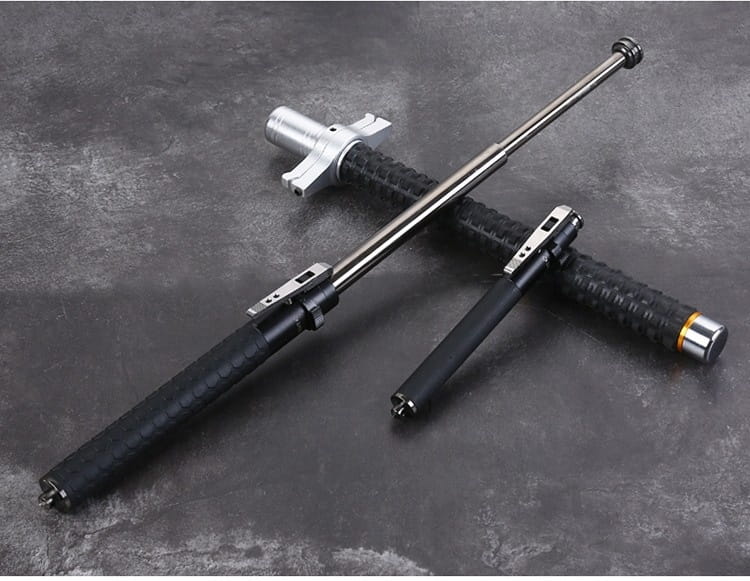 Black and silver automatic spring self-defense baton with aluminium alloy construction and textured grip handles.