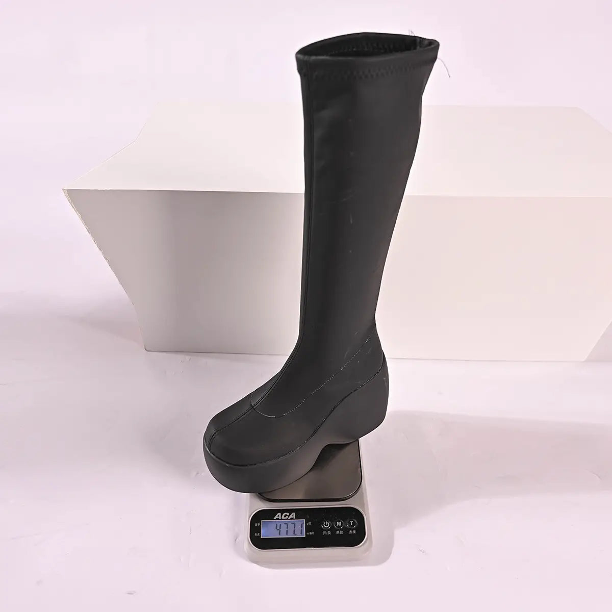Black platform knee high elastic leather boots featuring a sleek stretchy material and a thick wedge sole.