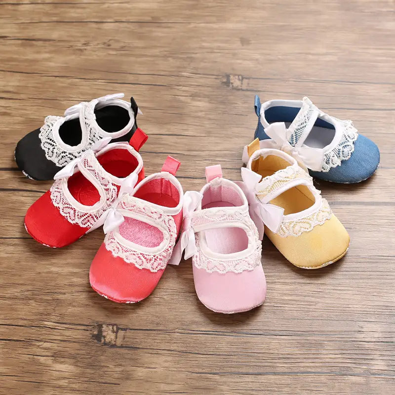 A set of princess shoes baby in soft pastel and bold colors featuring delicate white lace trim and matching bows on the front designed for baby toddler shoes.