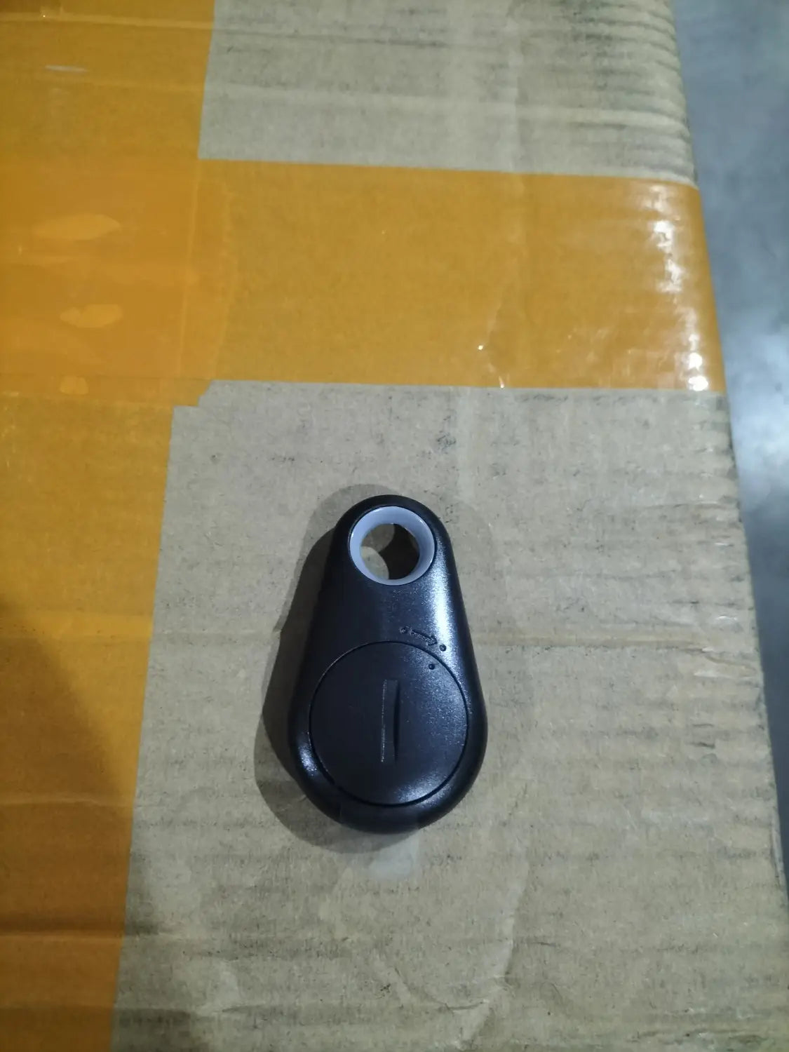 black plastic Bluetooth black water drop anti lost object finder with circular button and attachment hole designed as a lost object finder.