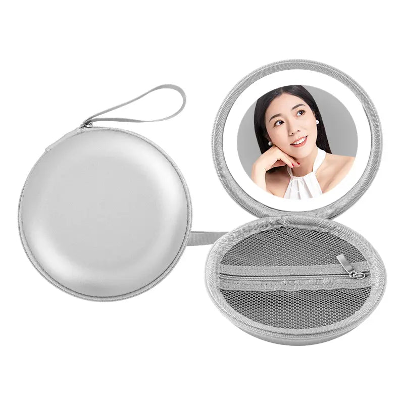 Silver oval compact mirror case with mesh interior and zipper featuring a circular reflective surface bordered by soft gray fabric trim in a round bag blue and silver round bag mirror case.