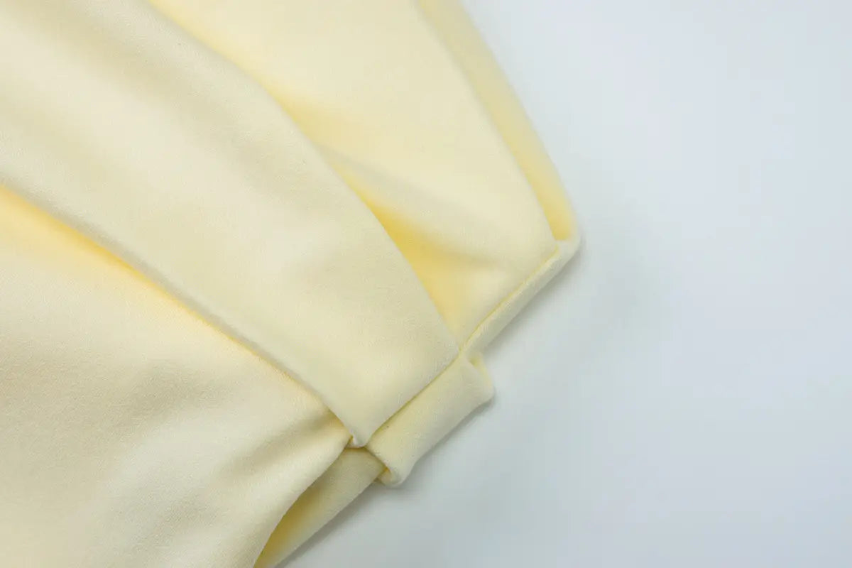 Soft pale yellow fabric with a smooth textured surface featured in a y2k lace suspender dress with burgundy satin accents.
