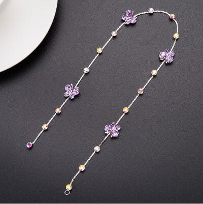 A delicate silver chain hair accessory adorned with sparkling purple butterfly charms and clear and yellow gemstones designed as wedding hair accessories.
