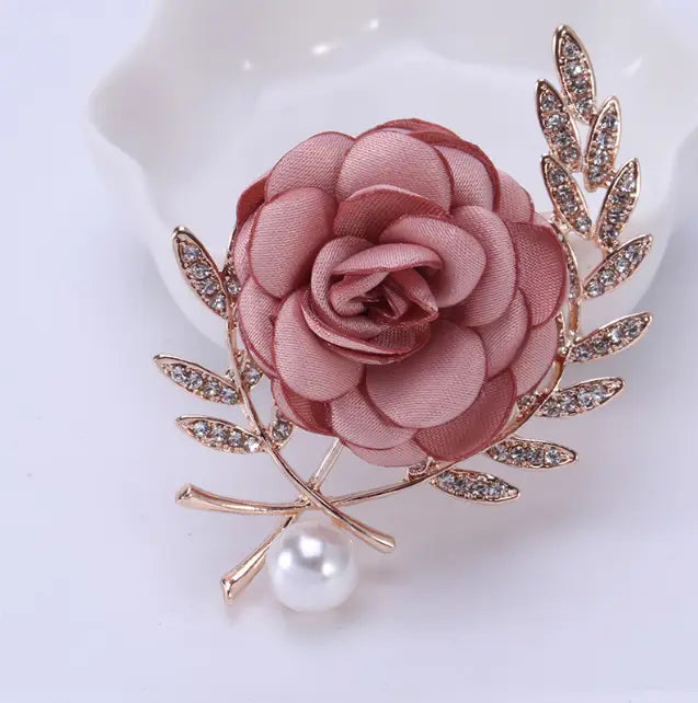 a delicate soft pink satin fabric flower lady brooch shaped like a rose with gold-toned leaf accents embedded with crystals and a dangling pearl, part of the lady temperamental pin floral brooch set